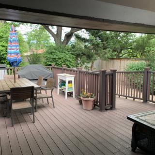 A spacious patio deck featuring outdoor furniture, a grill, and potted plants.