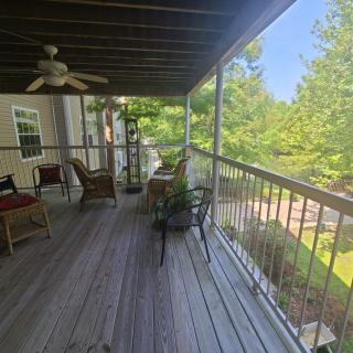 A cozy porch with outdoor furniture overlooking a lush green landscape.