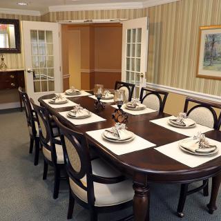 A formal dining room setup with a long table and chairs, elegantly arranged with place settings.