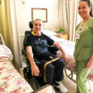 A nurse providing care to a patient in a wheelchair within a hospital room.