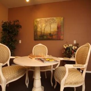 A cozy dining area with elegant chairs around a round table, adorned by a wall painting and indoor plant.