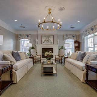 A beautifully decorated living room with sofas, a chandelier, and a fireplace.