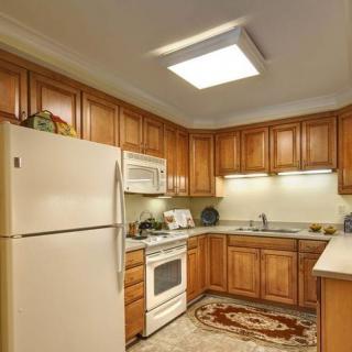 A cozy kitchen with wooden cabinets, equipped with a refrigerator, oven, and microwave.
