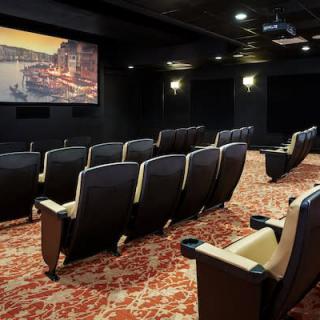 An empty theater room with a large screen and comfortable seating.