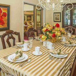 A formal dining room with a striped tablecloth, set with china and a floral centerpiece.