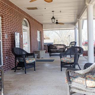 A cozy porch area with comfortable seating and a ceiling fan, perfect for relaxing outdoors.