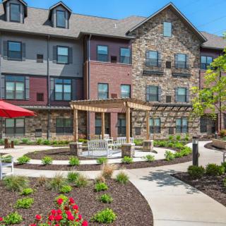 A modern residential building with a landscaped garden and outdoor seating area.