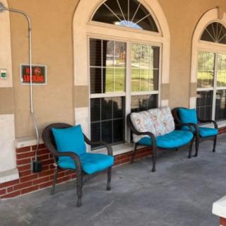 A cozy patio area with turquoise cushioned chairs and arched windows.