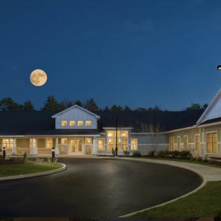 A building with a circular driveway is illuminated under a full moon at night.