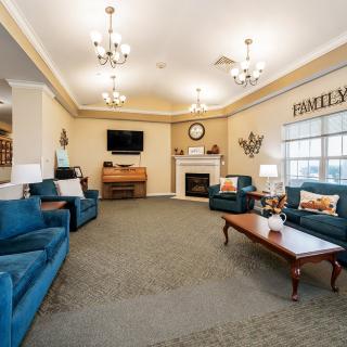 A cozy living room with blue sofas, a wooden coffee table, and a fireplace beneath a television.
