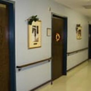 A hospital corridor with doors and framed pictures on the wall.