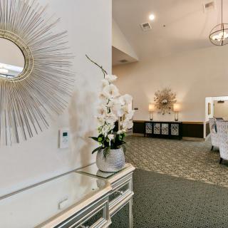 An elegantly decorated lobby featuring a starburst mirror and floral arrangements.