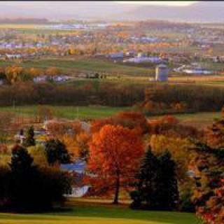 A scenic countryside landscape showcasing vibrant autumn colors with sprawling fields and trees.
