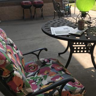 A cozy patio setting with a colorful cushioned chair, a round metal table, and a green balloon.