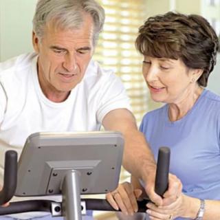 Senior couple engaging in a fitness routine on a stationary bike at home.
