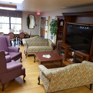 A cozy living room setup with patterned sofas, armchairs, and a large television.