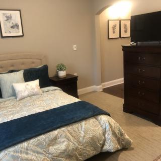 A cozy bedroom with a neatly made bed, dresser, and wall-mounted television.