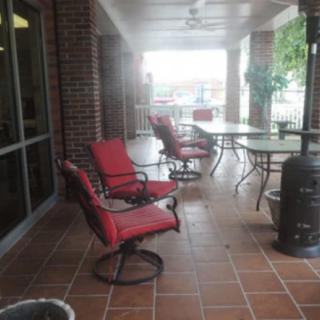 An outdoor patio area with red cushioned chairs and tables.