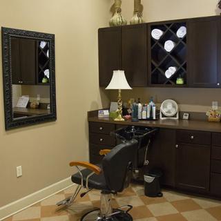 Interior of a salon with a styling chair, mirror, and cabinets.
