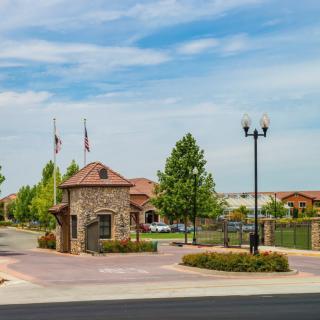 Entrance to a gated suburban community with a stone building and flags.