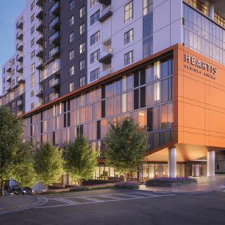 A modern hotel building with a sleek design and surrounding trees.