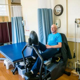 A senior man using exercise equipment in a rehabilitation setting.