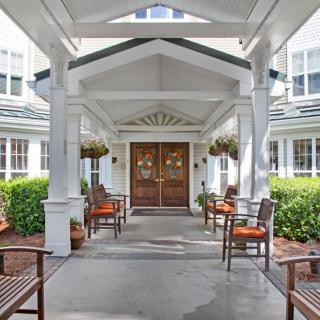 A welcoming building entrance with outdoor seating and decorative plants.