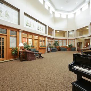 A spacious lobby with a grand piano, comfortable seating, and large windows allowing natural light.