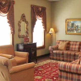 A cozy living room with traditional decor, featuring patterned sofas, armchairs, and a decorative rug.
