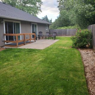 A well-maintained backyard with a grassy lawn, wooden deck, and fences on both sides.