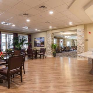 Spacious and well-lit dining area with elegant furniture and wooden flooring.