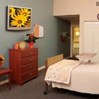 A cozy bedroom with a bed, dresser, and flower decorations.