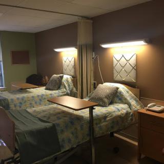 A hospital patient room featuring two beds and medical equipment.