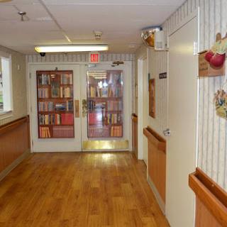 A peaceful hallway with wooden flooring and shelves filled with books.