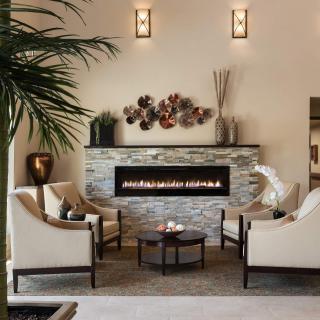 A modern living room featuring a sleek fireplace, elegant chairs, and tasteful decor.
