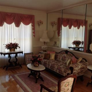 A vintage-style living room with floral furniture and mirrored walls.