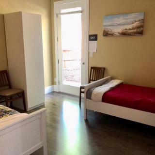 A minimalist bedroom with two single beds, a wardrobe, and artwork on the wall.