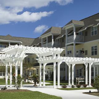 A modern residential building with a white pergola in the foreground.