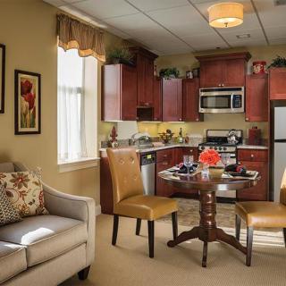 A cozy apartment interior featuring a modern kitchen and dining area with a sofa, table, and chairs.