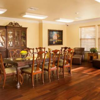 A spacious dining room with a wooden table and chairs, featuring elegant decor and warm lighting.