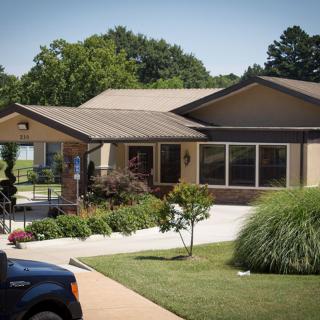 A suburban house with a driveway, garden, and parked car in the foreground.
