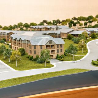 A detailed architectural model depicting a residential area with multiple buildings, roads, and surrounding greenery.
