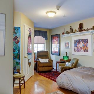 A cozy bedroom with posters on the walls and a comfortable chair by the window.