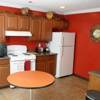 A kitchen with red walls, featuring wooden cabinets and white appliances.