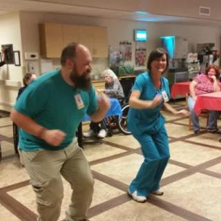 Healthcare workers dancing with residents in a nursing home.