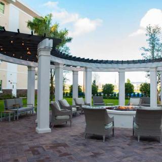 An outdoor patio with a pergola, featuring comfortable seating and a scenic garden view.