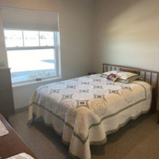 A cozy bedroom with a neatly made bed and a window letting in natural light.