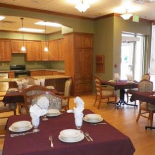 A cozy dining area featuring set tables and a view of an open kitchen.