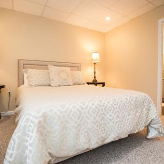 A cozy and well-decorated bedroom featuring a comfortable bed, soft lighting, and a neutral color palette.