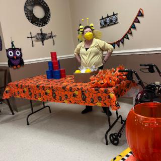 A festive Halloween-themed gathering featuring colorful decorations and a person in a playful costume.
